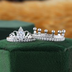 two silver crowns sitting on top of a green cushion