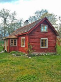 a red house sitting on top of a lush green field