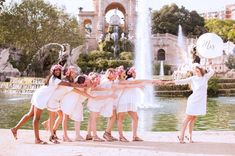 a group of women in white dresses standing next to each other with their arms around one another