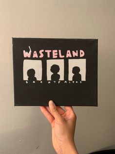 someone holding up a card with the words wasteland written in pink and black on it