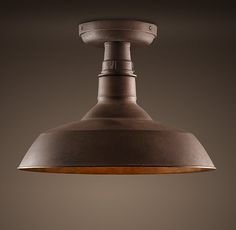 an industrial style light hanging from the ceiling in a room with dark walls and flooring