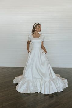 a woman in a white dress standing on a wooden floor with her back to the camera