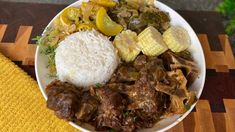 a white plate topped with meat and veggies on top of a wooden table