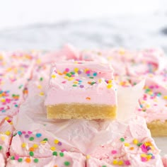 pink frosted cake with sprinkles on top and one slice cut out