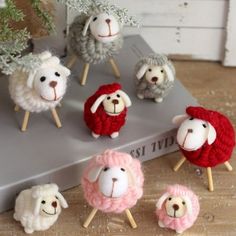 small sheep are sitting on top of a book with knitting needles in front of them