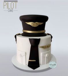 a three tiered cake with a pilot's hat and tie on the top