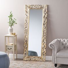 a large gold framed mirror sitting on top of a wooden floor next to a couch