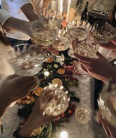 several people are holding wine glasses at a table with food and candles on it for a celebration