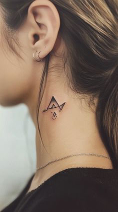 A small, minimalist black geometric tattoo on the side of a female neck, beautifully designed with clean lines. The photo captures the tattoo's subtle elegance without any inscriptions.