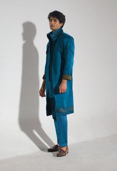 Editor's Note Step out in style with our teal overcoat, adorned with abstract handpaint detailing at the hem and collar. Paired with a tone on tone shirt kurta and tapered trousers, this ensemble exudes elegance and sophistication. Perfect for both formal and semi-formal occasions, it's a versatile outfit that will make a lasting impression. Fabric: Linen silk Color: Blue Component: Overcoat, kurta and trousers Occasion: Formals Note: Product colour may slightly vary due to photographic lighting Fitted Kurta For Workwear In Fall, Fitted Blue Nehru Jacket For Fall, Traditional Blue Kurta For Fall, Blue Long Sleeve Kurta For Fall, Winter Cotton Straight Kurta Set, Cotton Straight Kurta Set For Winter, Blue Shacket, Painted Borders, Blouse Yoke