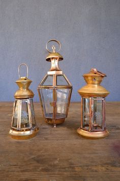 three brass lanterns sitting on top of a wooden table