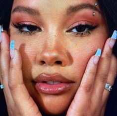 a woman holding her hands to her face with makeup on top of her head and nails in front of her face