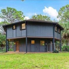 a house in the middle of a grassy area with trees and bushes around it,