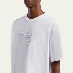 Prada T-shirt with silicone logo at chest Crew neckline Short sleeves Boxy fit Pullover style Cotton Made in Italy Luxury Logo Print Tops For Streetwear, Luxury Short Sleeve Top With Designer Logo, Luxury Crew Neck Top With Logo Print, Luxury Crew Neck Top For Streetwear, Luxury Streetwear Tops With Designer Logo, Luxury Logo Print Crew Neck Top, Luxury Logo Crew Neck Top, Luxury Designer Logo T-shirt For Streetwear, Luxury Designer Logo Tops For Streetwear