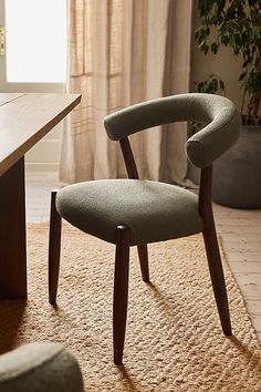 a chair sitting on top of a rug in front of a wooden table and window