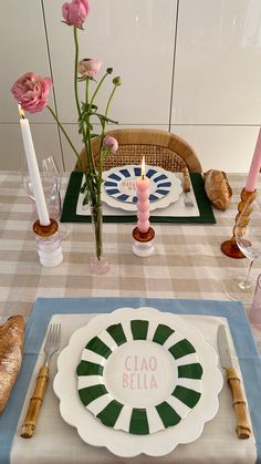 a table setting with plates, candles and flowers on the place mat in front of it