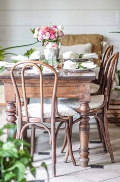 a dining room table with chairs and flowers on it