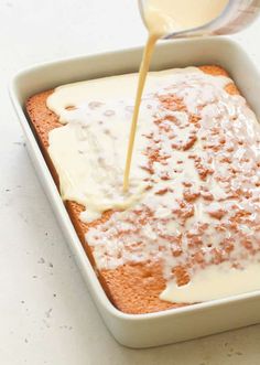 a pan filled with cake covered in icing and being drizzled over