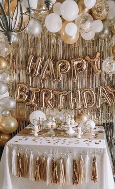 a birthday party with gold and white balloons, streamers, tassels and confetti