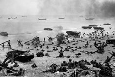 an old black and white photo of people on the beach with boats in the water