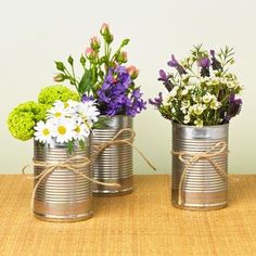 three tin can vases with flowers in them