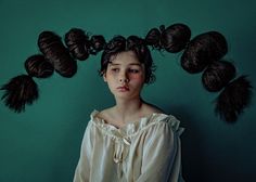 a woman with her hair in the shape of balls on her head, against a green background