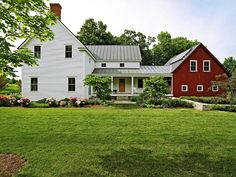 a white house with a red front door and two stories on the side of it