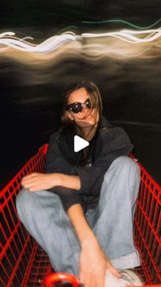 a woman sitting in a shopping cart with her legs crossed and sunglasses on, looking at the camera