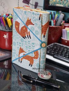 an open notebook sitting on top of a desk next to a pen and pencil holder