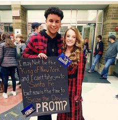 a man and woman standing next to each other holding a sign