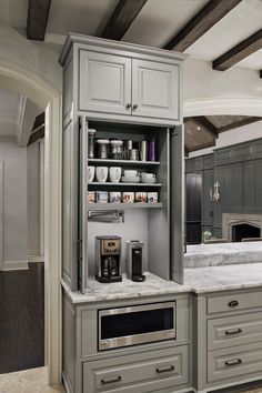 a kitchen with gray cabinets and white counter tops, an oven and coffee maker in the corner