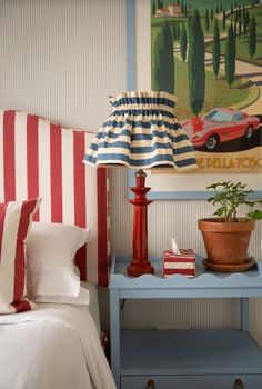 a blue table with a lamp on it next to a red and white striped headboard