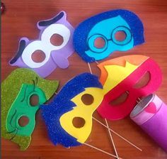 some colorful masks are sitting on a table with pins and thread in them to make it look like they have been made out of paper