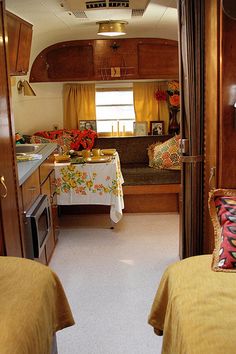 the inside of a camper with two beds and a table in front of it