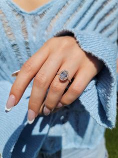 a woman's hand with a ring on her finger and a light blue sweater