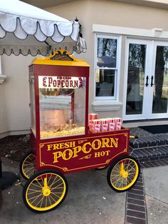 an old fashioned popcorn machine sitting in front of a house