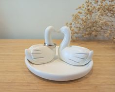 two white swan figurines sitting on top of a wooden table