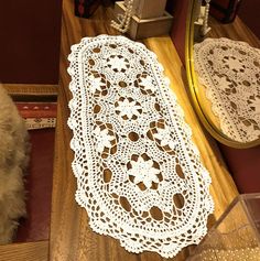 a white doily sitting on top of a wooden table next to a small mirror