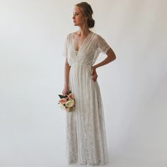 a woman in a long white dress holding a bouquet and looking off to the side