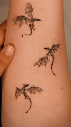 a woman's arm with three small dragon tattoos on the left side of her body