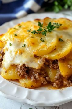 a white plate topped with lasagna covered in cheese and meat on top of it