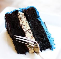 a piece of chocolate cake with blue icing and white frosting on a plate