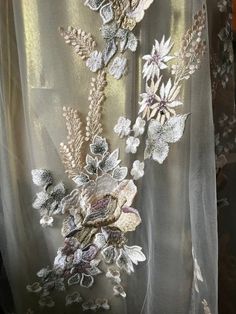 an embroidered dress with flowers and leaves on the front, along with sheer fabric behind it