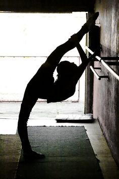 a woman is doing yoga in front of a door with her hands on the bars