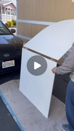 a woman unpacking a white box in front of a car on the street