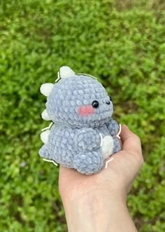 a hand holding a small gray crocheted stuffed animal