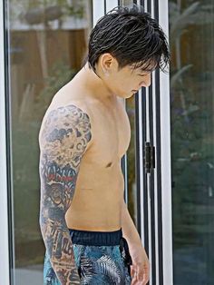 a man with tattoos standing in front of a glass door