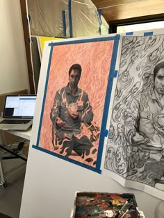 two paintings are hanging on a wall next to a laptop computer and other art work