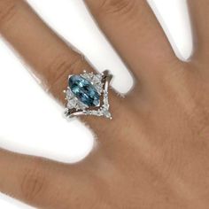 a woman's hand with a blue and white diamond ring on top of it