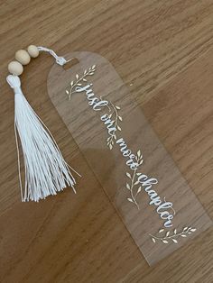 a wooden table topped with a clear sign and tassel